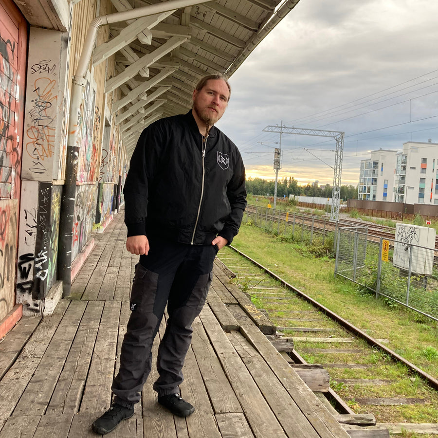 Rurik Fightgear-lentäjänpusakka.
Rurik FG "R" -logo rintapielessä sekä riimulogo selässä monivärisesti brodeerattuna. Kuvassa pilottitakki  Mikan päällä junan laiturilla. PT-Combat.Fi