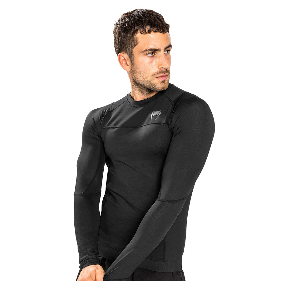 Venum G-Fit Air Long-Sleeve Rashguard. Tyylilkäs musta väri. Kuvassa rashguard kuvattuna viistosti miehen päällä. pt-combat.fi